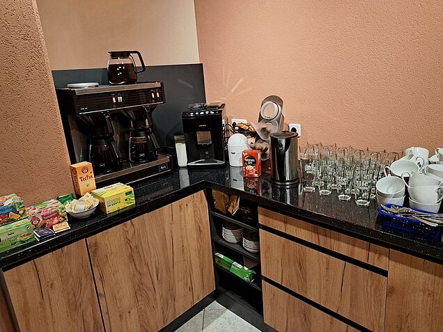 warme Getränkebuffet in Holzoptik und schwarz mit Filterkaffeemaschine, Siemens Kaffeeautomat mit Latte Macchiato, Americano, Espresso, Capuccino, Cafe Crema, daneben Wasserkocher, Gläser und Tassen, außerdem verschiedene Teesorten von Teekanne